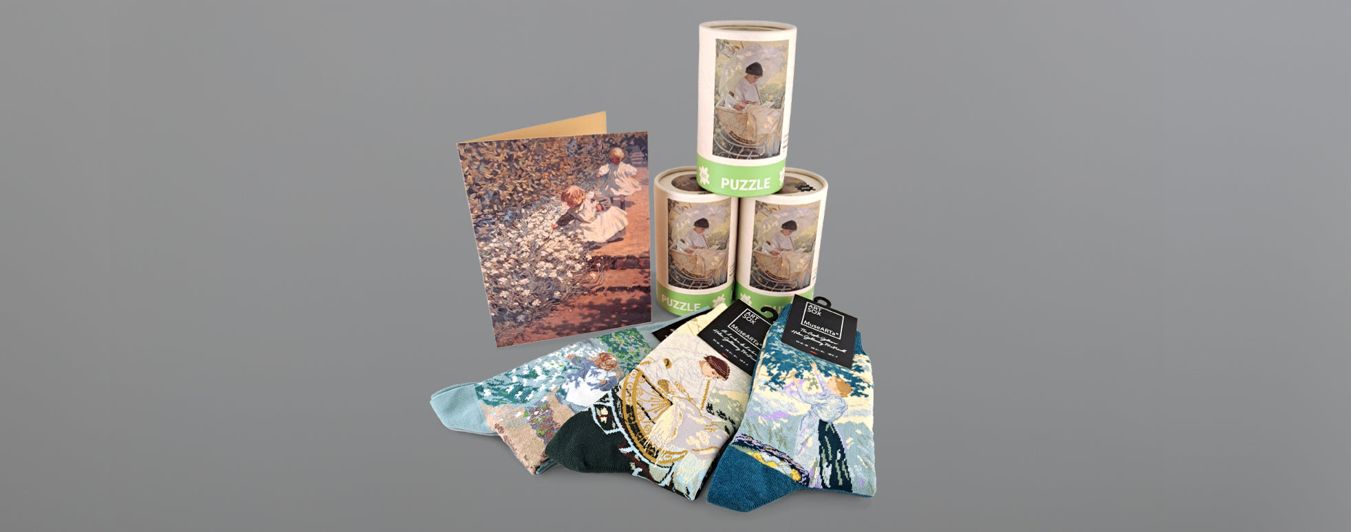 Cards, puzzles and socks featuring Helen McNicoll's artworks displayed on a grey background.